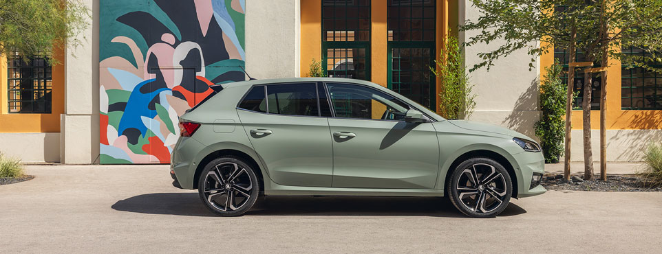 Zu sehen ist ein gelber Skoda Kodiaq vor einer Skyline