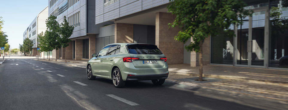 Ein grüner Škoda Fabia vor einem Gebäude.